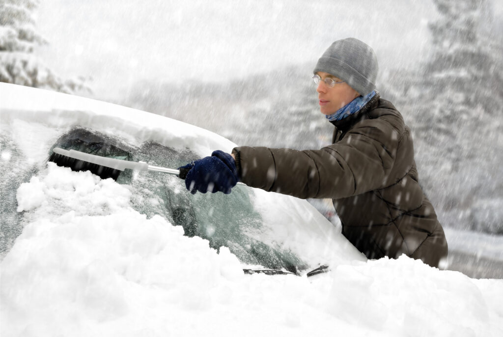 Man removes snow form car's windshield