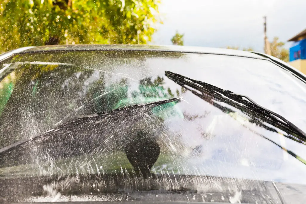 outdoor view of car wipers wash windshield when driving in rain