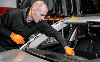Car glazier cleaning car's dashboard during windshield replacement process