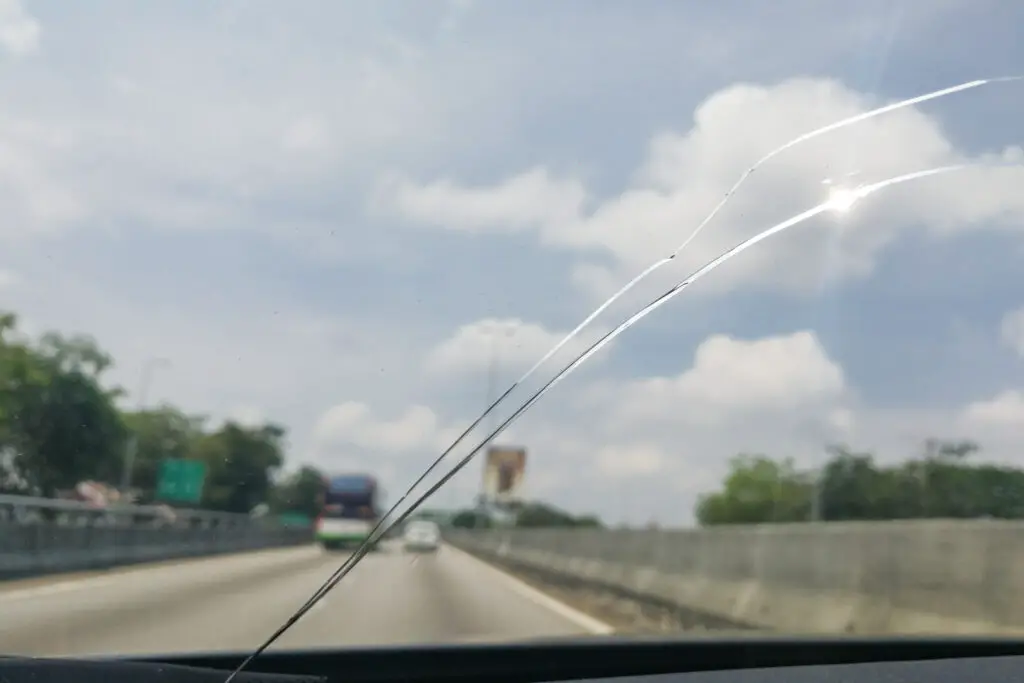 Perspective view of cracked car windshield from inside vehicle while driving