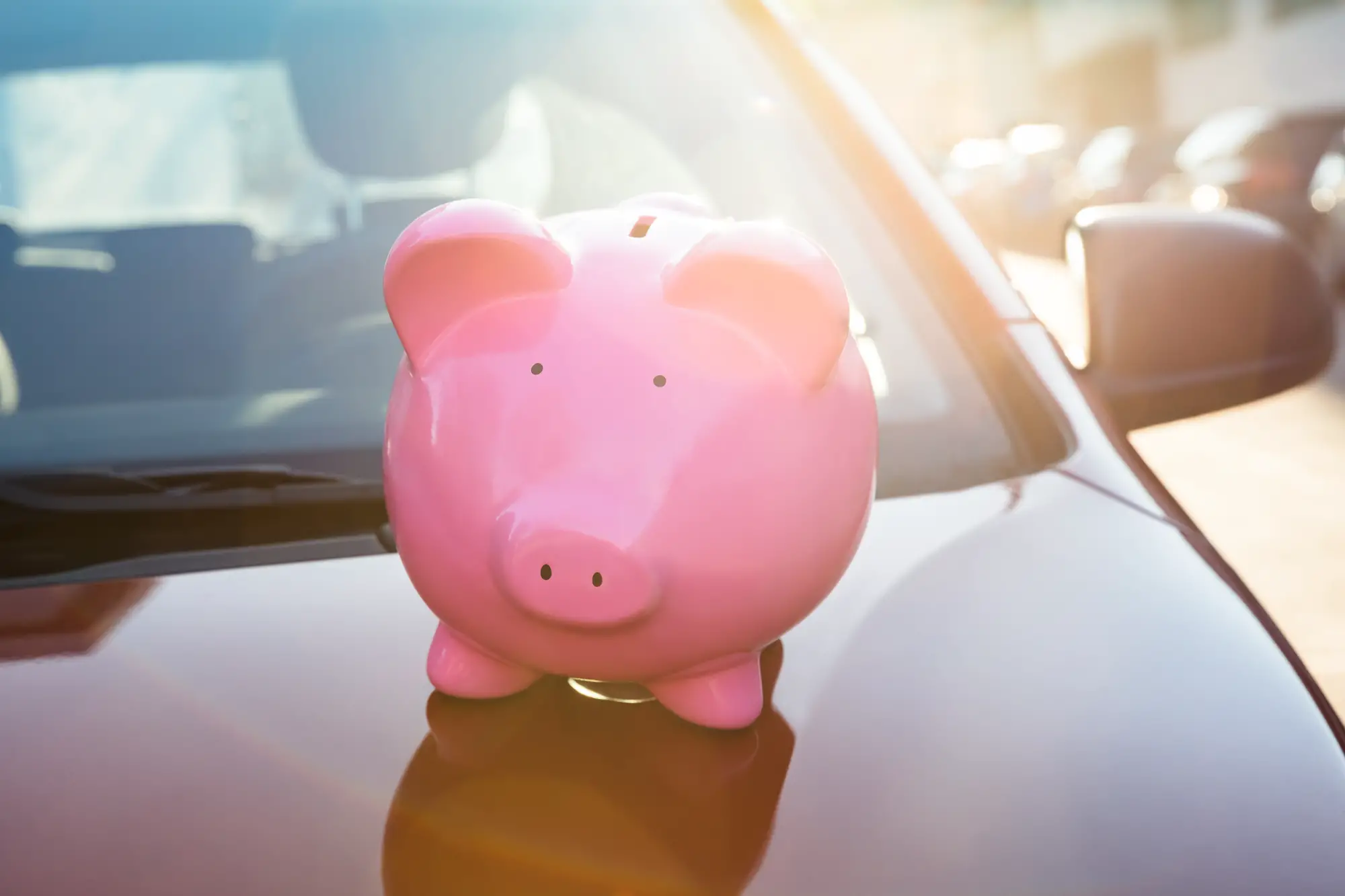 Piggybank on car in front of windshield