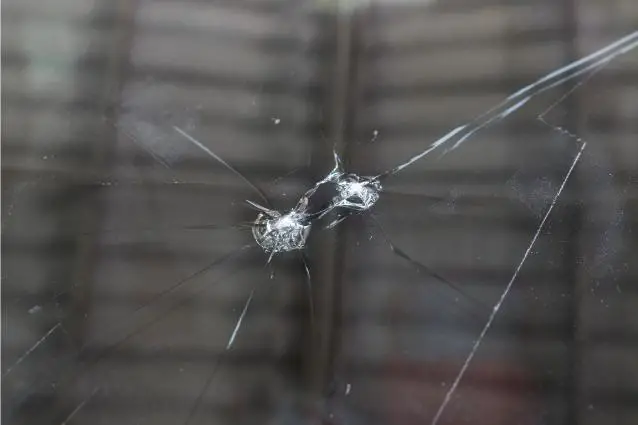 Multiple stone chips and cracks on a windshield, close up