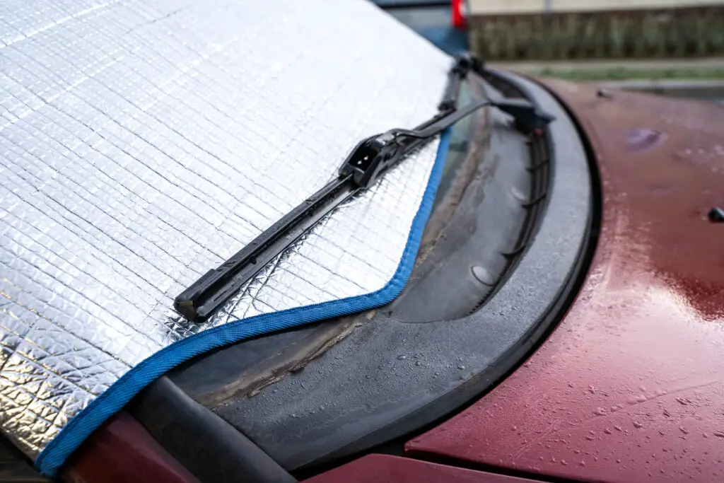 Car with protective windshield cover in cold morning. Cover protects windshield from ice