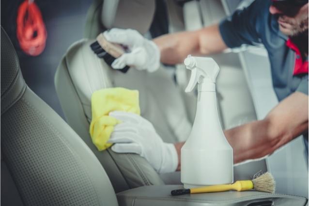 All necessary materials for leather seat cleaning process, man cleans leather seat with brush in a background