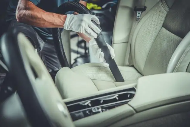 Person in a white nitrile gloves vacuum clean white car leather seats