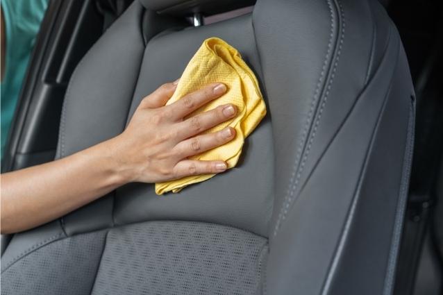 Person wiping out all dirt and excessive cleaning solution with microfiber towel from leather seat 