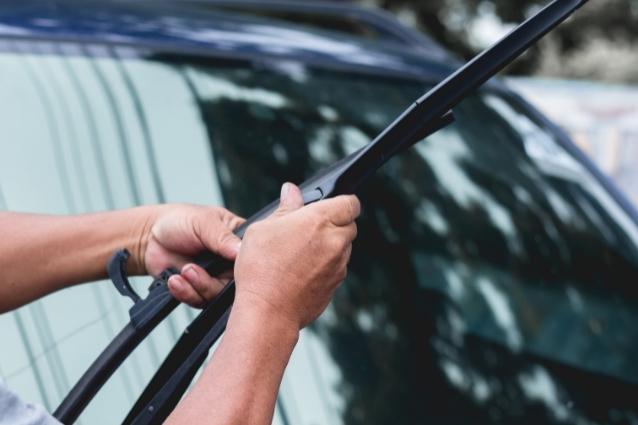 Person is replacing windshield wipers on the vehicle, close up photo