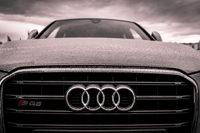 Front of a Audi SQ5, Close-up of car logo on the front grill, rain outside.