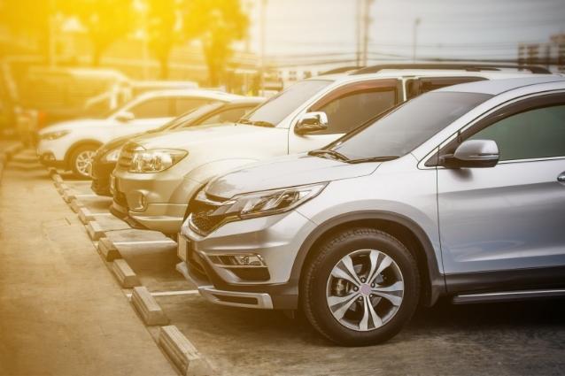 Different cars parked on a parking lot. Sun is shining bright.