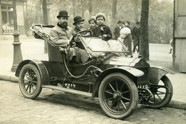Family on a vintage car from 1900's, black and white photo.