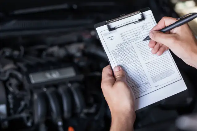 Car technician is performing inspection of the vehicle, mark of checklist