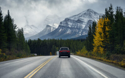 Beautiful view of the car driving on empty road of Alberta, Mountains and forest on the background