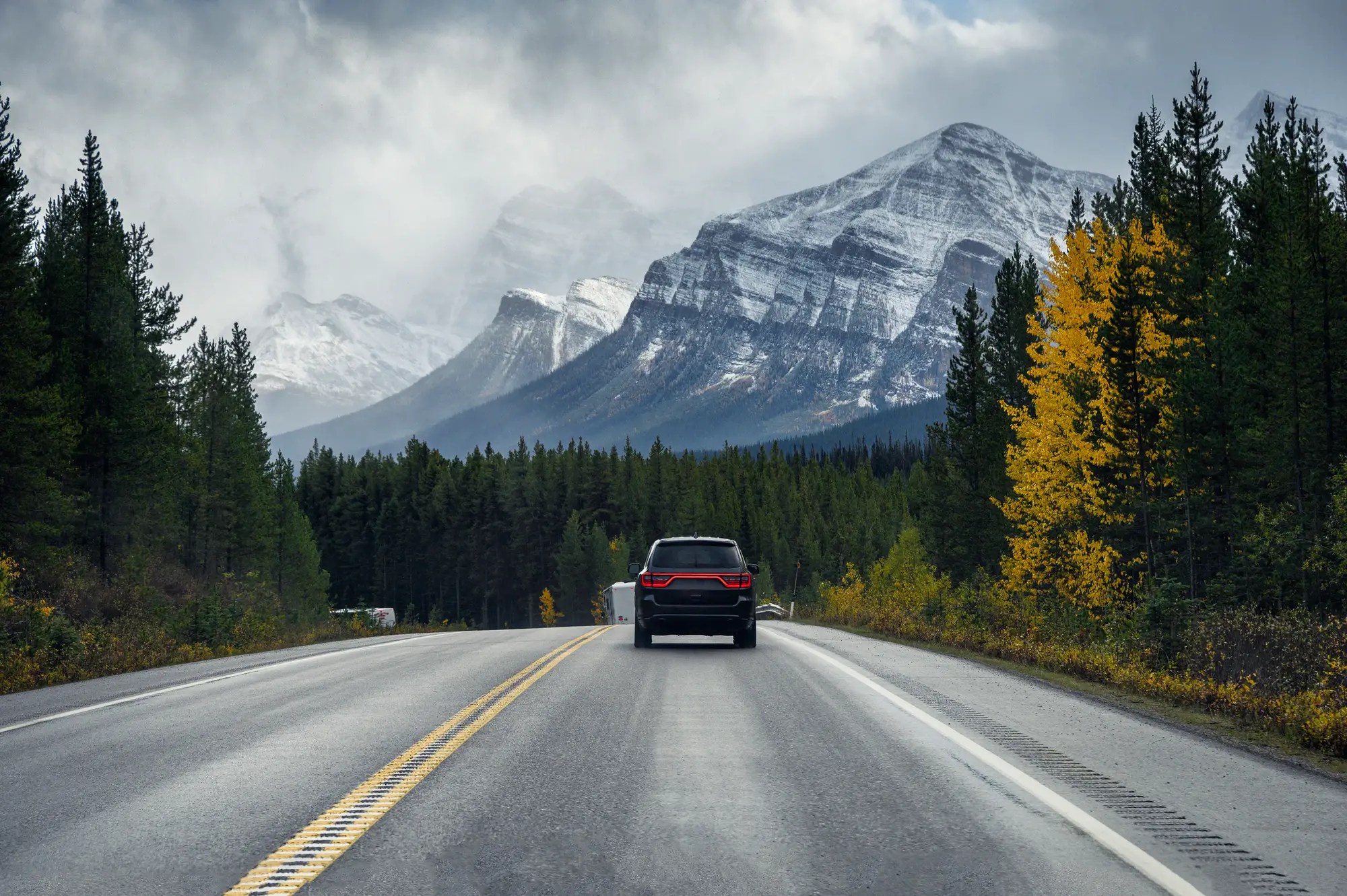 Beautiful view of the car driving on empty road of Alberta, Mountains and forest on the background
