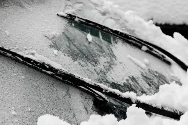 Wiper blades cleaning out snow and ice from the car's windshield in winter, close up 