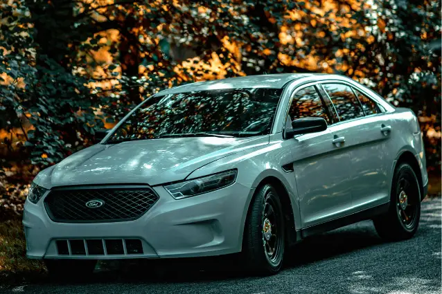 Nice looking white Ford sedan car with custom wheels on the street.